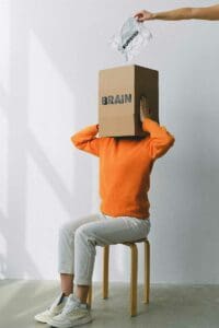 a person sitting on a chair with a box on their head